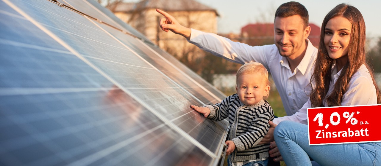 Eine Familie sitzt vor einem Dach mit Photovoltaik-Anlage